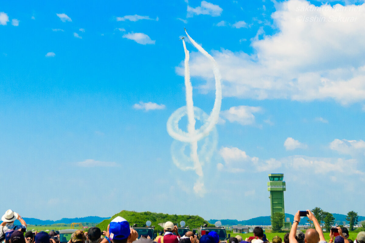 松島基地で撮影したブルーインパルスの演目「コークスクリュー」。2機がスモークを引いて飛ぶ姿と観覧する人々
