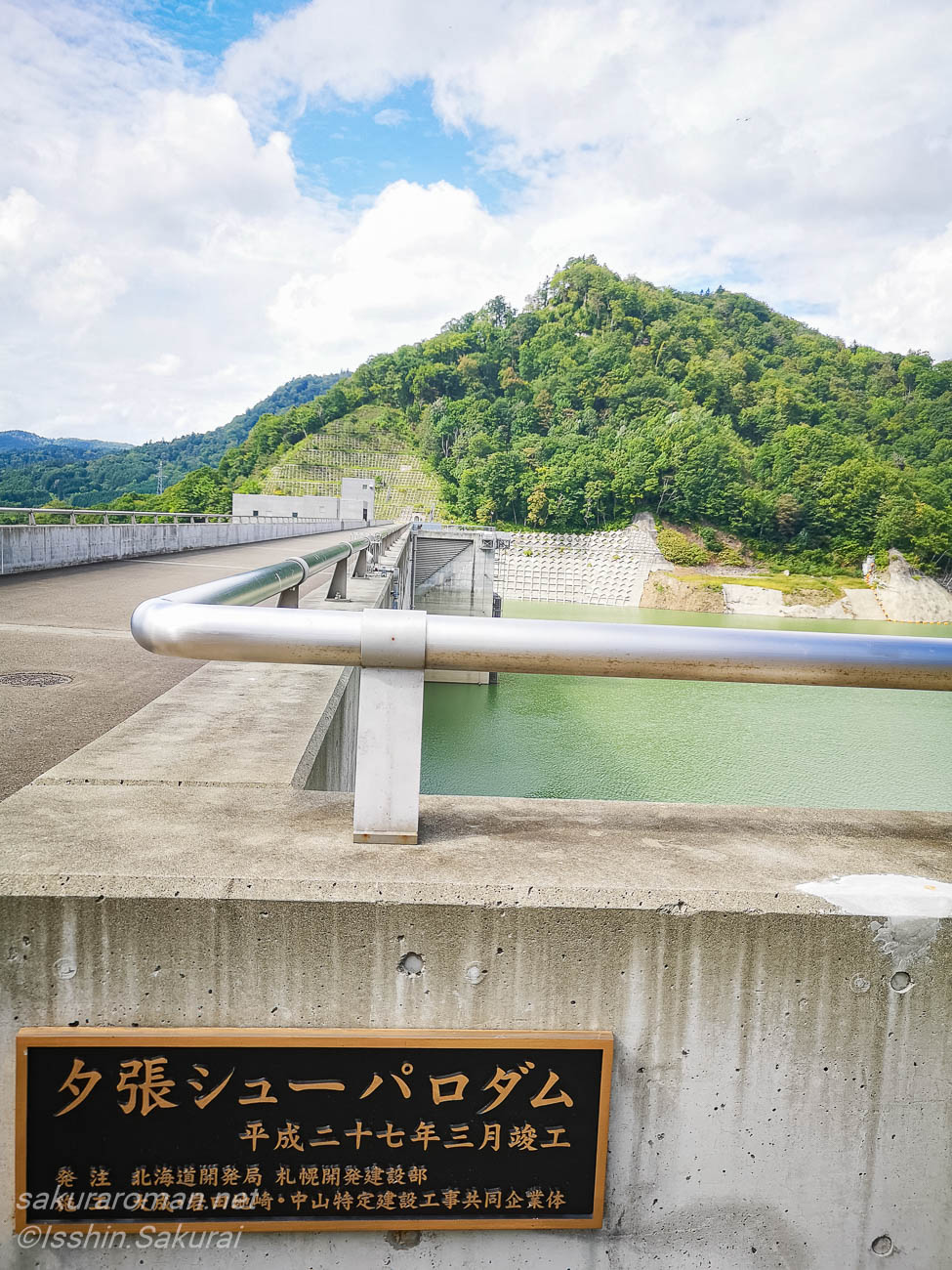 夕張シューパロダムの銘板と堤体上から望むシューパロ湖周辺の山並み