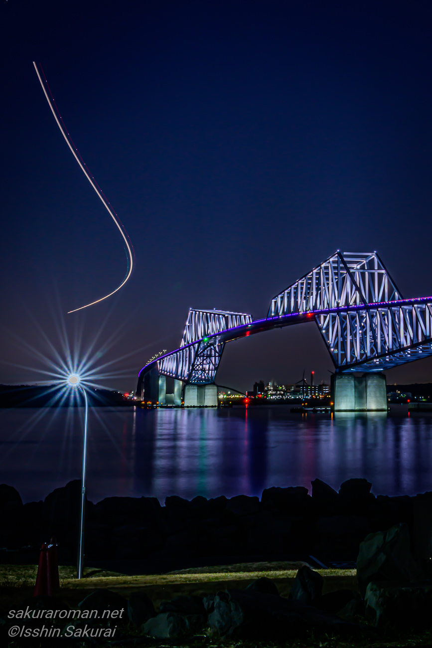 飛行機の光跡とライトアップされた東京ゲートブリッジの夜景